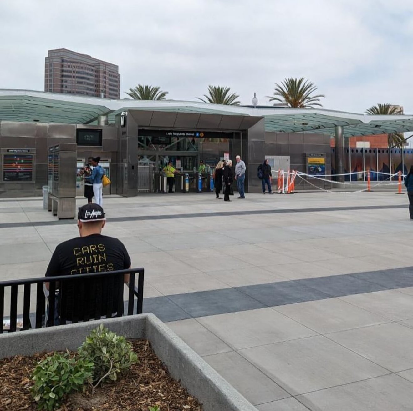 Photo of Adam Linder outside of a Metro station wearing a 'Cars Ruin Cities' shirt and an 'LA' hat.